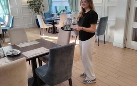 Uczennica podaje do stołu karafkę z wodą i szklanki