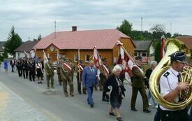 Przemarsz orkiestry dętej i poczt&oacute;w sztandarowych ulicami Oleszna do kościoła parafialnego