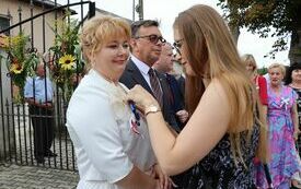Pracownica Starostwa przypina kotylion Członek Zarządu Powiatu Włoszczowskiego