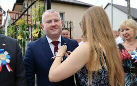 Pracownica Starostwa przypina kotylion Wicestaroście Włoszczowskiemu