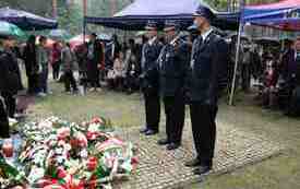 Składanie kwiat&oacute;w pod pomnikiem.