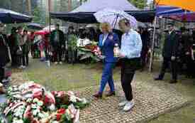 Składanie kwiat&oacute;w pod pomnikiem.