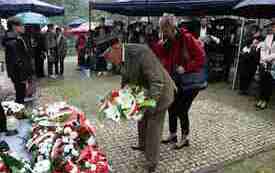 Składanie kwiat&oacute;w pod pomnikiem.