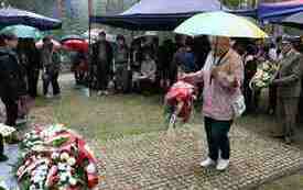 Składanie kwiat&oacute;w pod pomnikiem.