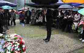 Składanie kwiat&oacute;w pod pomnikiem.