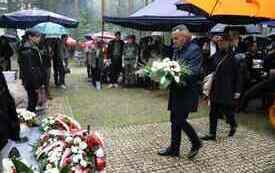 Składanie kwiat&oacute;w pod pomnikiem.