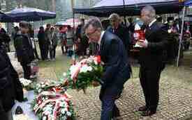 Składanie kwiat&oacute;w pod pomnikiem.