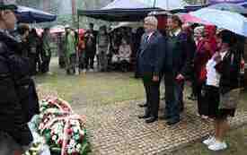 Składanie kwiat&oacute;w pod pomnikiem.