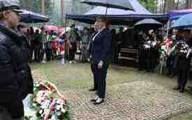 Składanie kwiat&oacute;w pod pomnikiem.