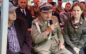 Z mikrofonem w ręce kombatant w żołnierskim mundurze.