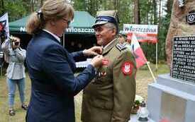 Przedstawicielka ministra przypina medal do piersi żołnierza w zielonym mundurze. 