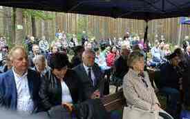 Uczestnicy uroczystości siedzą pod namiotem.