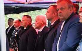 Uczestnicy uroczystości siedzą pod namiotem.