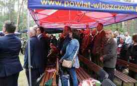 Uczestnicy uroczystości stoją pod namiotem.