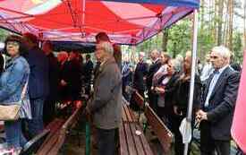 Uczestnicy uroczystości stoją pod namiotem.