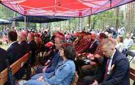 Uczestnicy uroczystości siedzą pod namiotem.