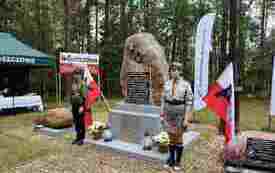 Przy obelisku udekorowanym flagami narodowymi warę pełnią harcerze.
