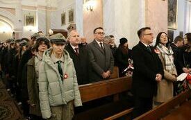 Uczestnicy uroczystości stoją przy ławach kościelnych. Na piewszym planie Starosta i Wicestarosta.