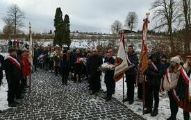 Poczty sztandarowe i delegacje stoją na placu małego cmentarza