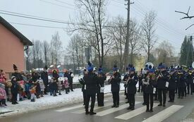 Przemarsz uczestnik&oacute;w uroczystości z zakładu do kościoła. Na czele Młodzieżowa Orkiestra Dęta OSP Krasocin. 