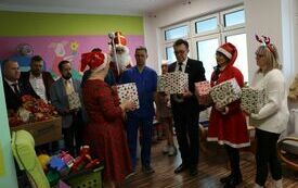 Mikołaj i jego pomocnicy wręczają paczki dyrektorowi ZOZ i lekarzom pracującym na oddziale pediatrycznym