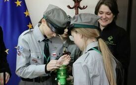 Harcerka zapala świeczkę ogniem z przyniesionego lampionu z Betlejemskim Światłem Pokoju