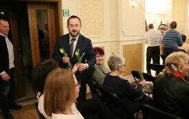 Panowie wręczają wszystkim obecnym na sali paniom tulipany