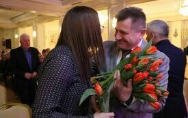 Panowie wręczają wszystkim obecnym na sali paniom tulipany