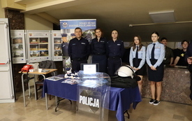 Stoisko policji. Za stołem policjanci i uczniowie klasy mundurowej.
