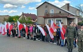 Dzieci stoją w szeregu trzymając w rękach flagi Polski