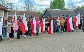 Dzieci stoją w szeregu trzymając w rękach flagi Polski