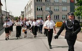 Orkiestra i pozostali uczestnicy uroczystości maszerują sprzed Urzędu Gminy do kościoła
