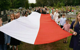 Dzieci trzymają ogromną flagę Polski