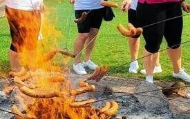 Uczestniczki Olimpiady pieką kiełbaski na ognisku
