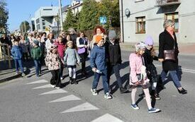 Uczestnicy uroczystości maszerują ulicą Partyzant&oacute;w z kościoła do szkoły