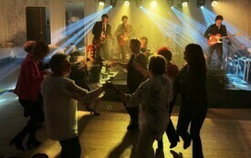 Zesp&oacute;ł występuje na scenie, a przed sceną publiczność tańczy w k&oacute;łku