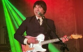 Jeden z członk&oacute;w zespołu gra na gitarze i śpiewa do mikrofonu