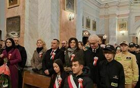 Uczestnicy mszy stoją w ławach kościelnych. Na pierwszym planie przedstawiciele Urzędu Gminy Włoszczowa.