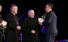 Dyrektor Caritas Diecezji Kieleckiej wręcza na scenie staroście statuetkę, dziekując mu za wsparcie