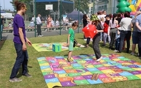 Dzieci bawiące się pod opieką animatora na plenerowej grze planszowej