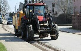 Traktor z urządzeniem do zamiatania jedzie ulicą Ogrodową