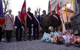 Poczty sztandarowe stoją przed pomnikiem Jana Pawła II
