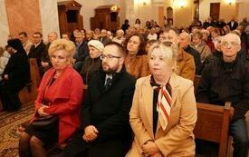 Wierni siedzą w ławkach kościelnych