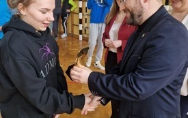 Członek Zarządu Powiatu Włoszczowskiego Rafał Pacanowski wręcza jednej z zawodniczek statuetkę