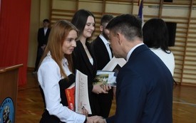 Poseł Bartłomiej Dorywalski wręcza nagrodę jednej z maturzystek Zespołu Szk&oacute;ł nr 3 we Włoszczowie 