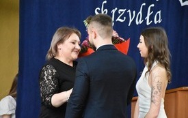 Przedstawiciele klas maturalnych wręczają dyrektorce bukiet kwiat&oacute;w