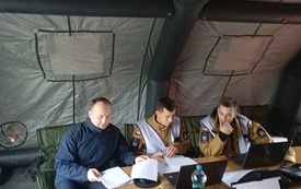 Wewnątrz namiotu strażackiego siedzi zesp&oacute;ł nadzorujący ćwiczenia