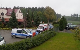 Na parkingu stoją samochody policyjne i karetka