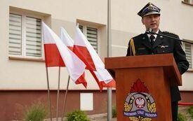 Przy m&oacute;wnicy ustawionej przed budynkiem Urzędu Gminy Krasocin przemawia Komendant Powiatowy Państwowej Straży Pożarnej we Włoszczowie