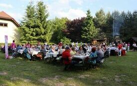 W plenerze, przy stołach siedzą uczestnicy Maj&oacute;wki